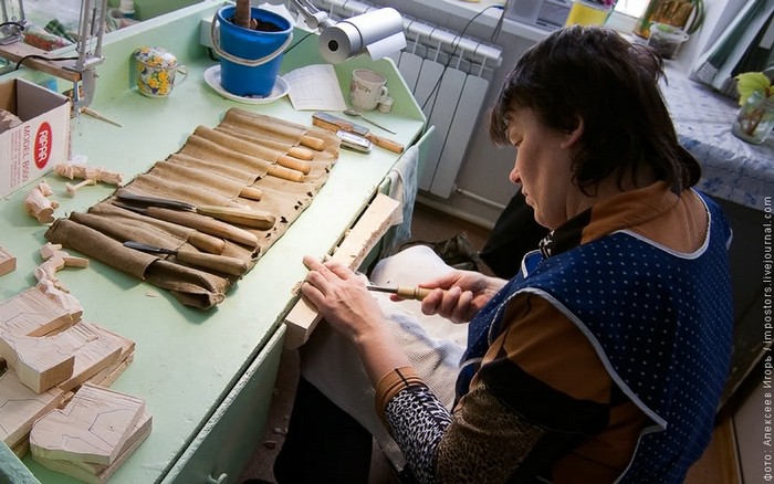 Một nữ thợ thủ công bên chiếc bàn đầy các dụng cụ đục, đẽo
